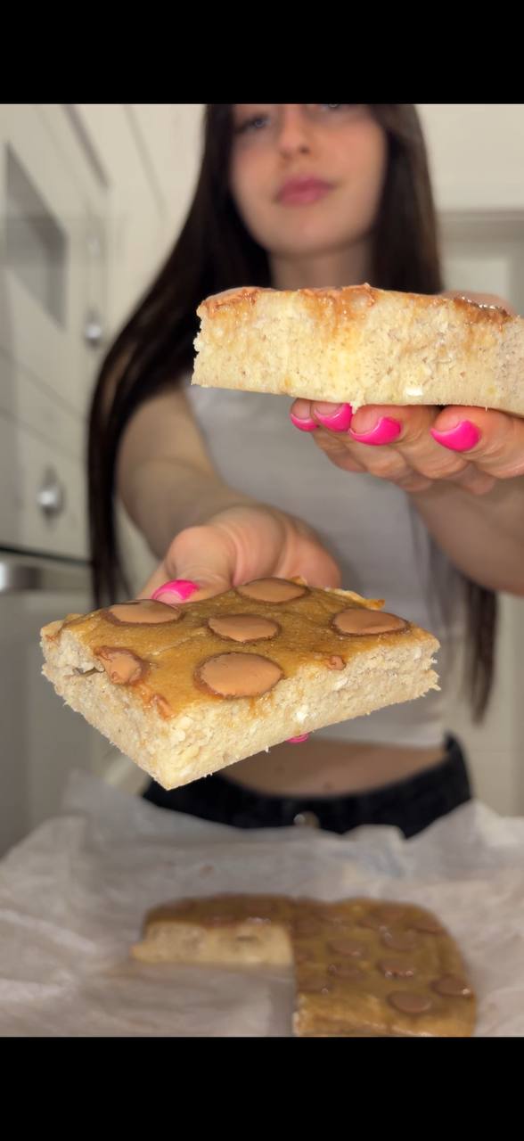Sofia holding a slice of banana bread peanut blondie with a bite taken out
