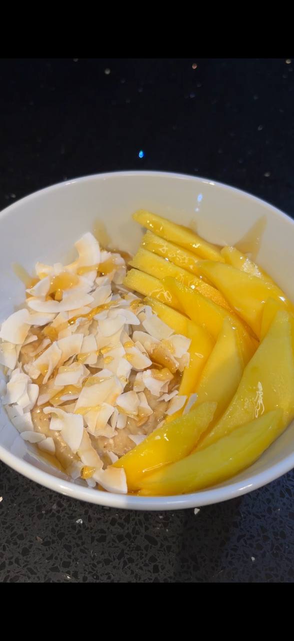 Mango sticky oats with coconut flakes and honey drizzle top view