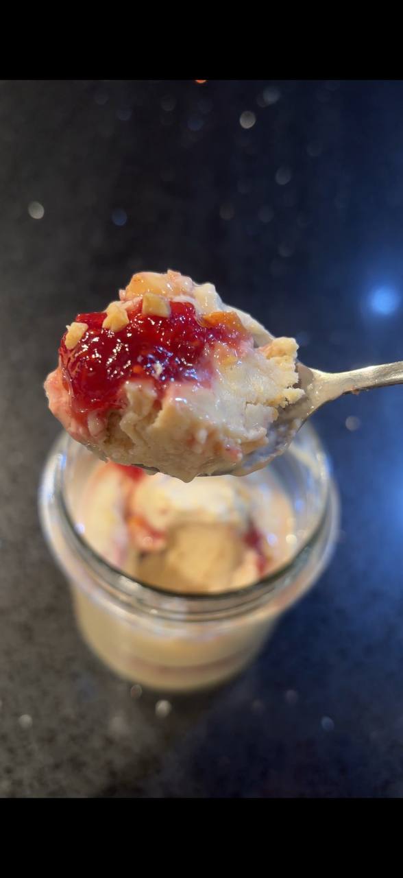 Spoonful of creamy pistachio ice cream with raspberry jam close up