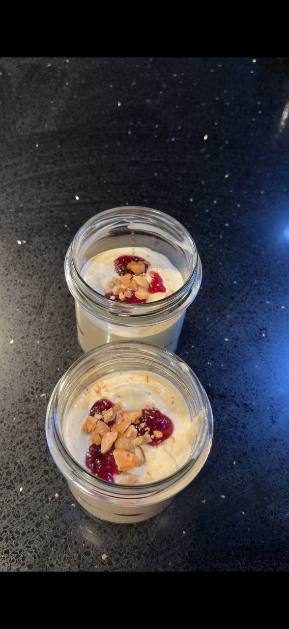 Two jars of pistachio ice cream with raspberry and crushed pistachios