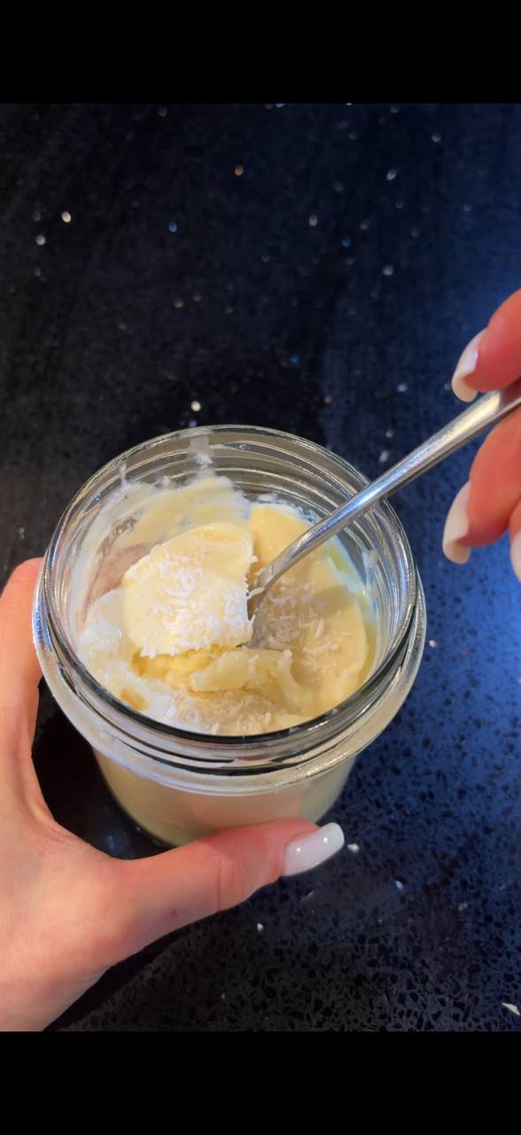 Tropical smoothie bowl in a jar with spoon and coconut flakes close up